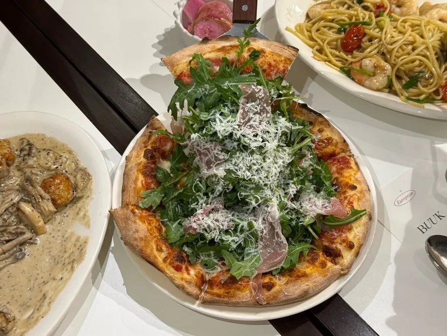 A slice of prosciutto pizza showing cheese and dough