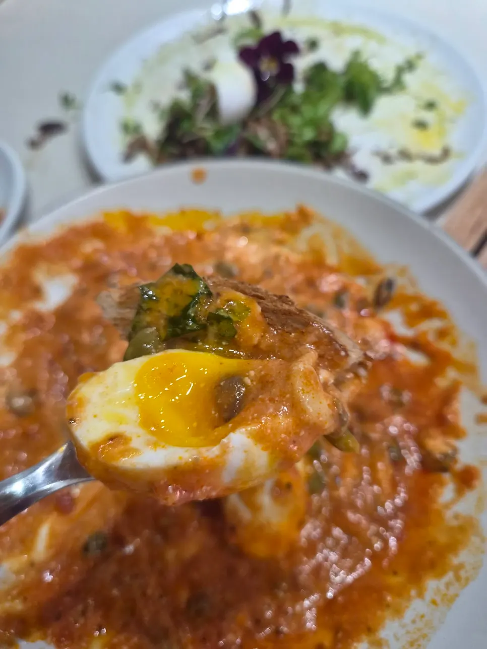 A bite of egg-in-hell with bread dipped in sauce