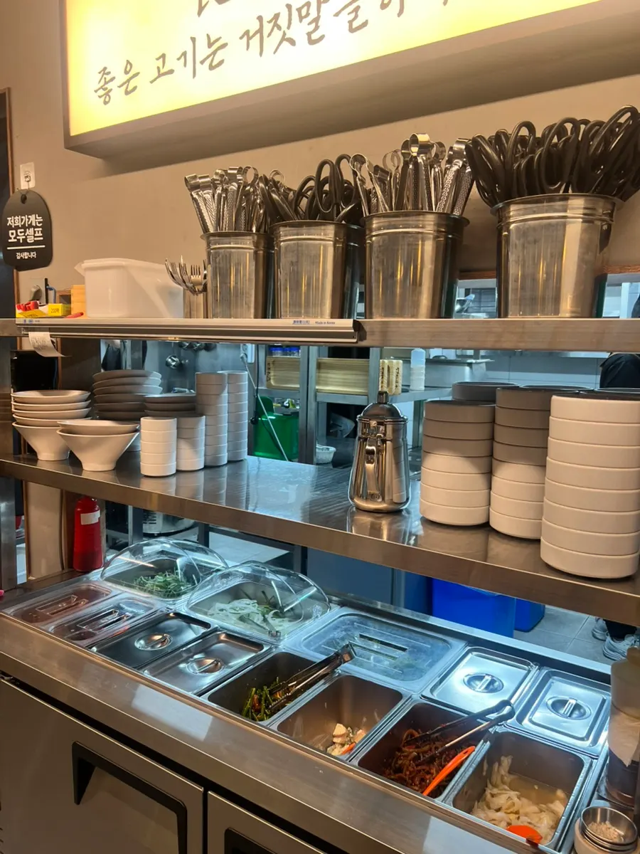 Self-serve bar at Yangsimso Ansan Gojan Branch stocked with side dishes and sauces