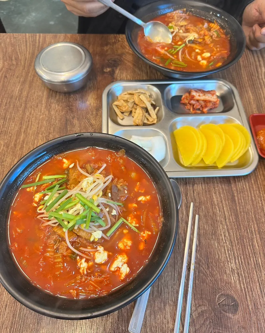 Table set with chicken jjamppong, mini jajangmyeon, and side dishes