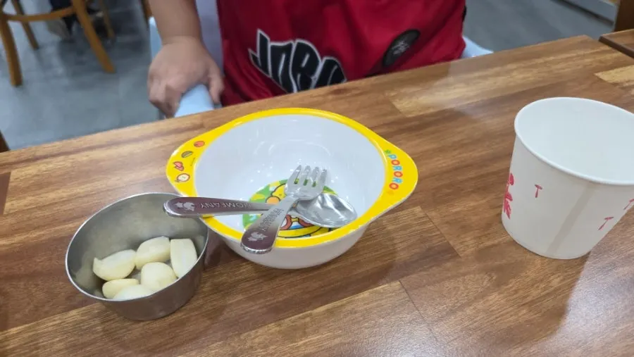 Table set up with kids' tableware and a baby chair at Yeoyejeong