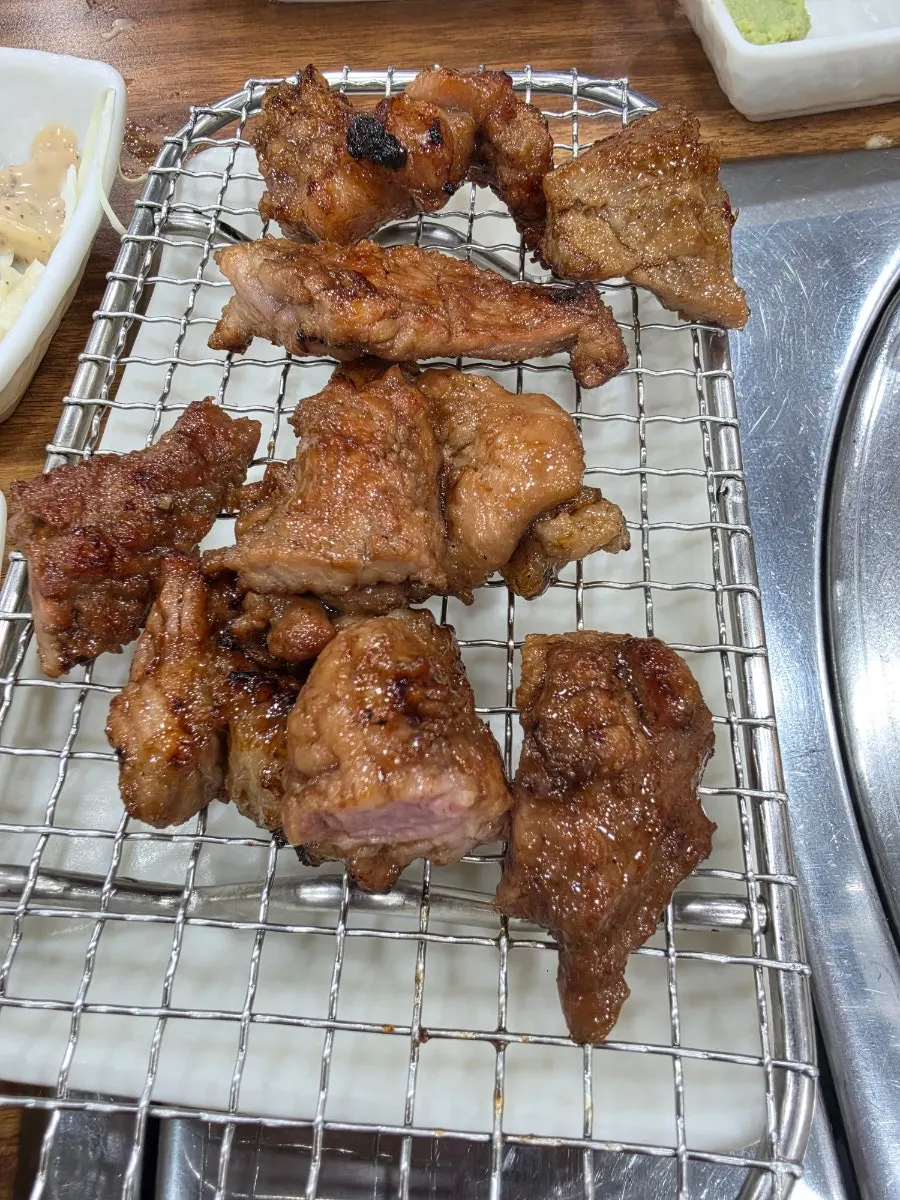 Grilled meat set aside on a heat-venting plate