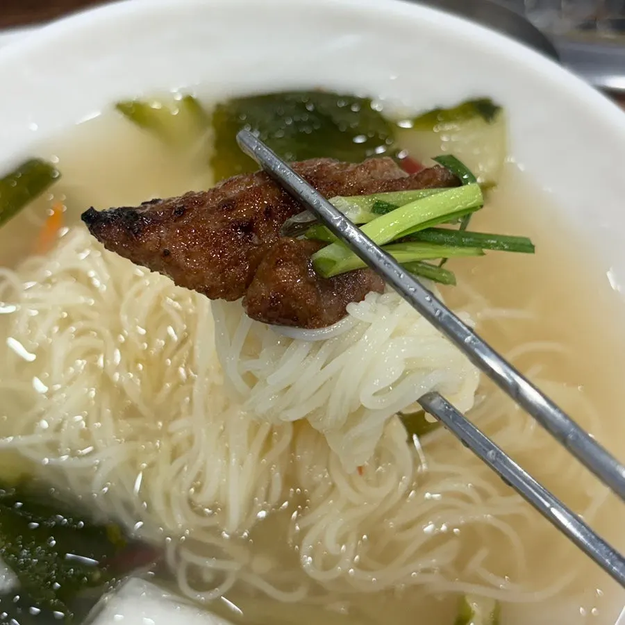 Noodles sitting in white kimchi broth