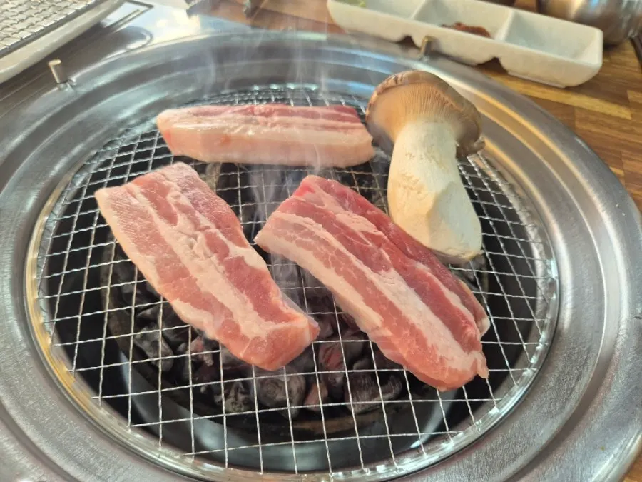 Pork belly grilling over charcoal