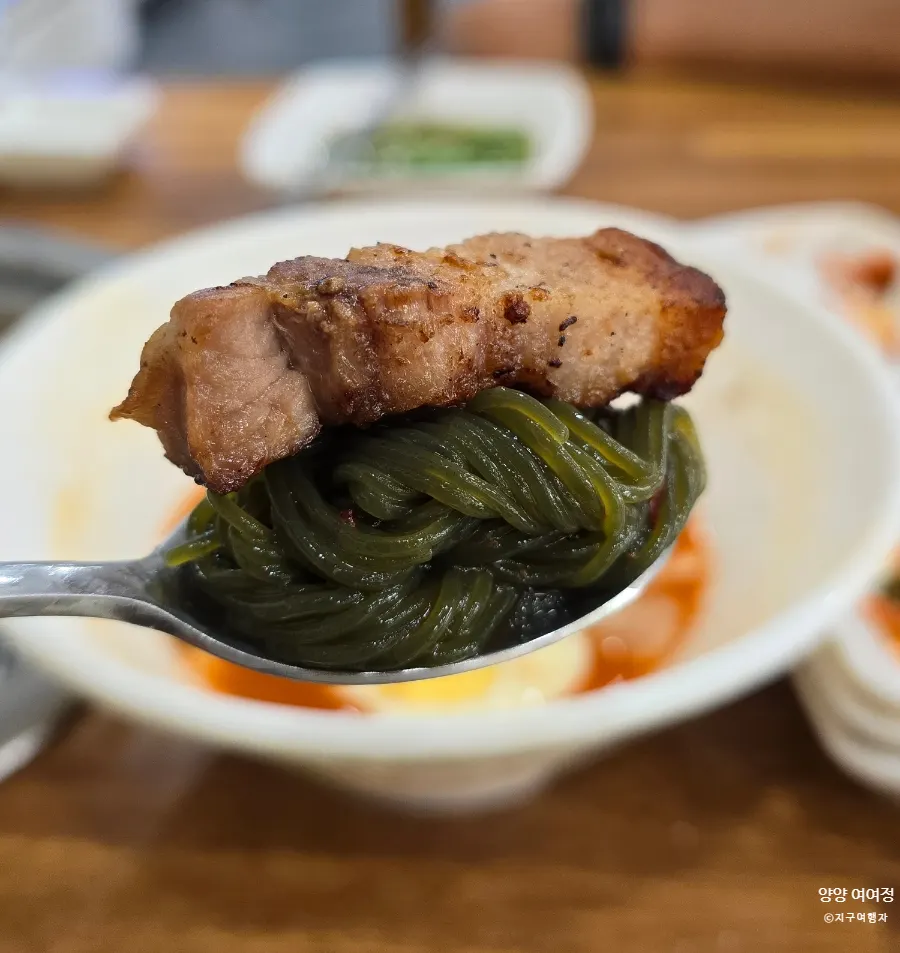 초록색 면이 담긴 냉면 육수
