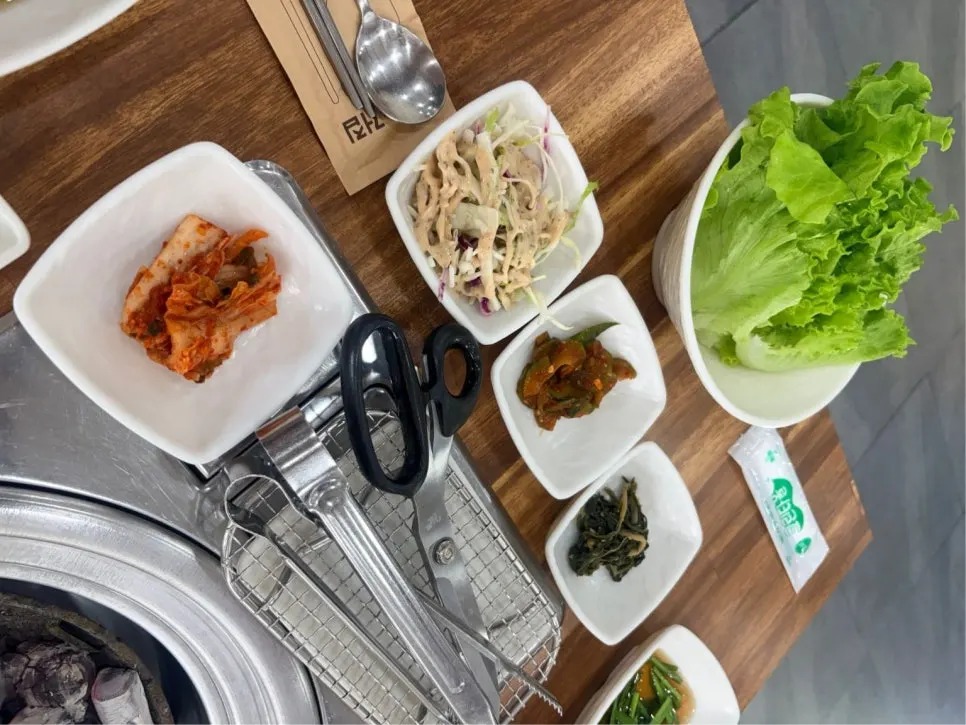 Side dish spread with lettuce, pickles, and salad