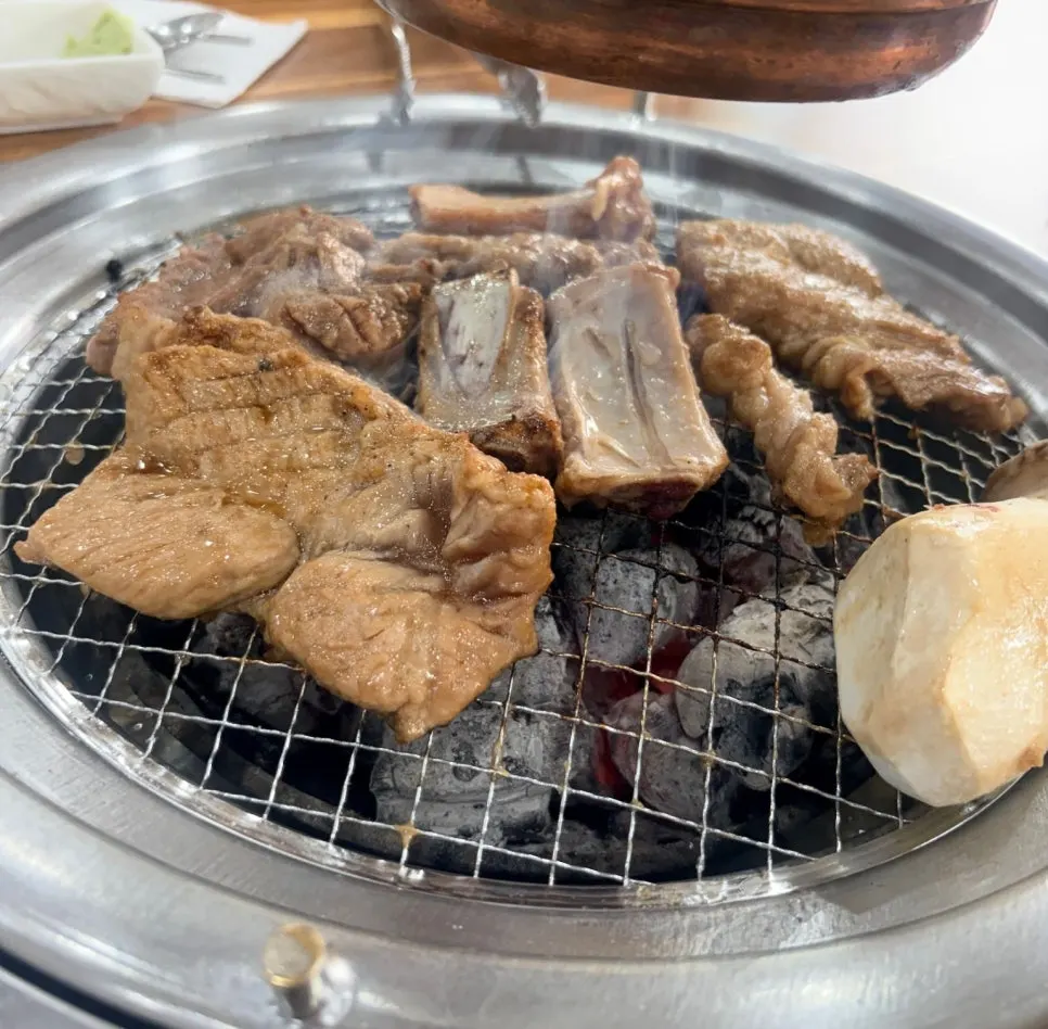 Marinated galbi being flipped over charcoal