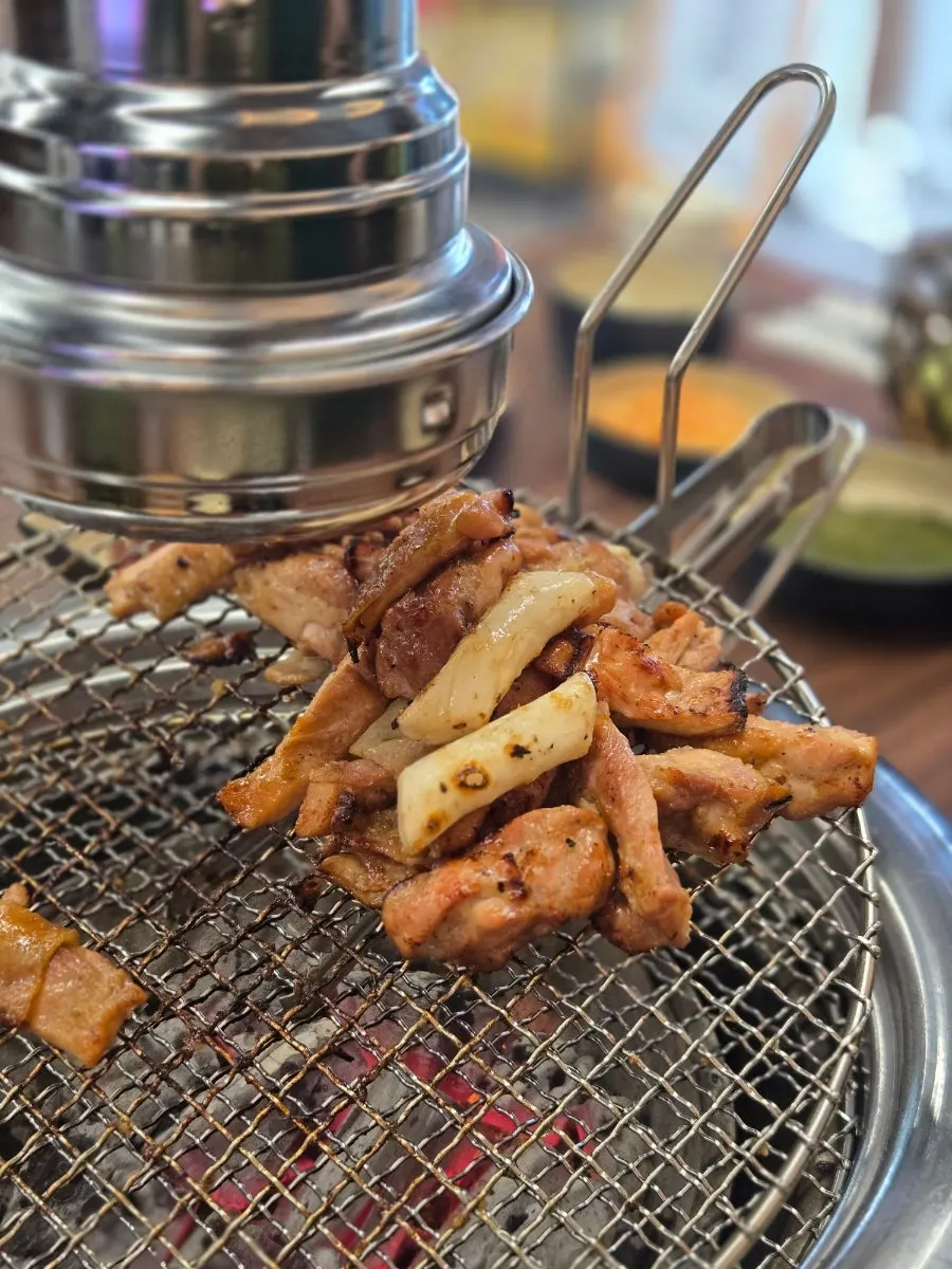 Staff-grilled dakgalbi piled to one side of the grill