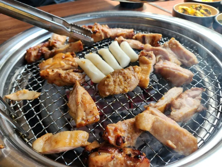Soy sauce dakgalbi and rice cake sticks grilling golden brown over charcoal