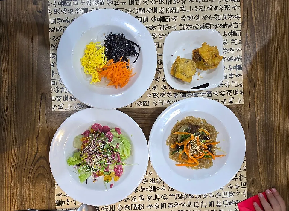 Starter spread of salad, mung bean jelly, japchae, and fried eggplant