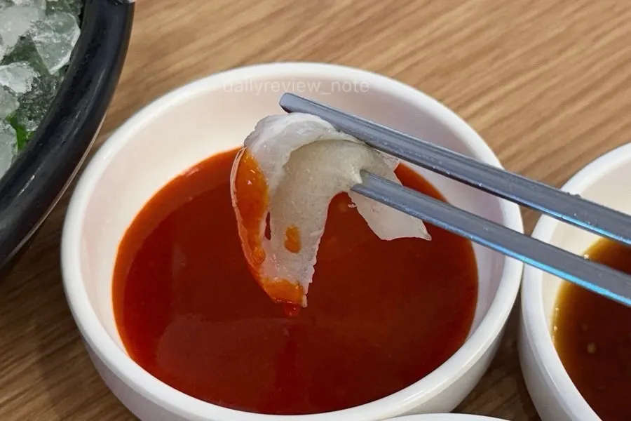 A piece of sashimi topped with soy sauce and wasabi