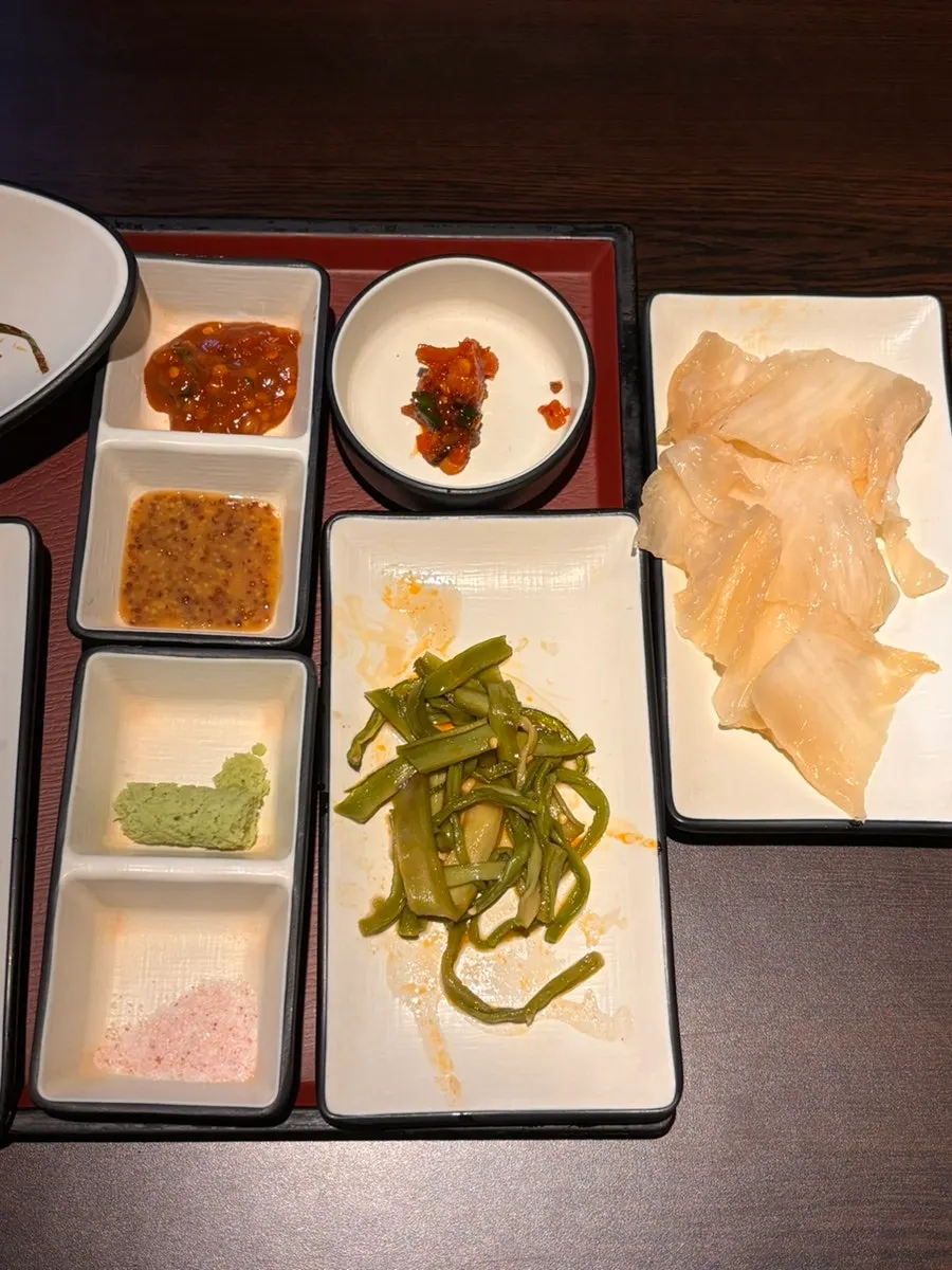 Side dishes of wild garlic leaves, white kimchi, and sauce
