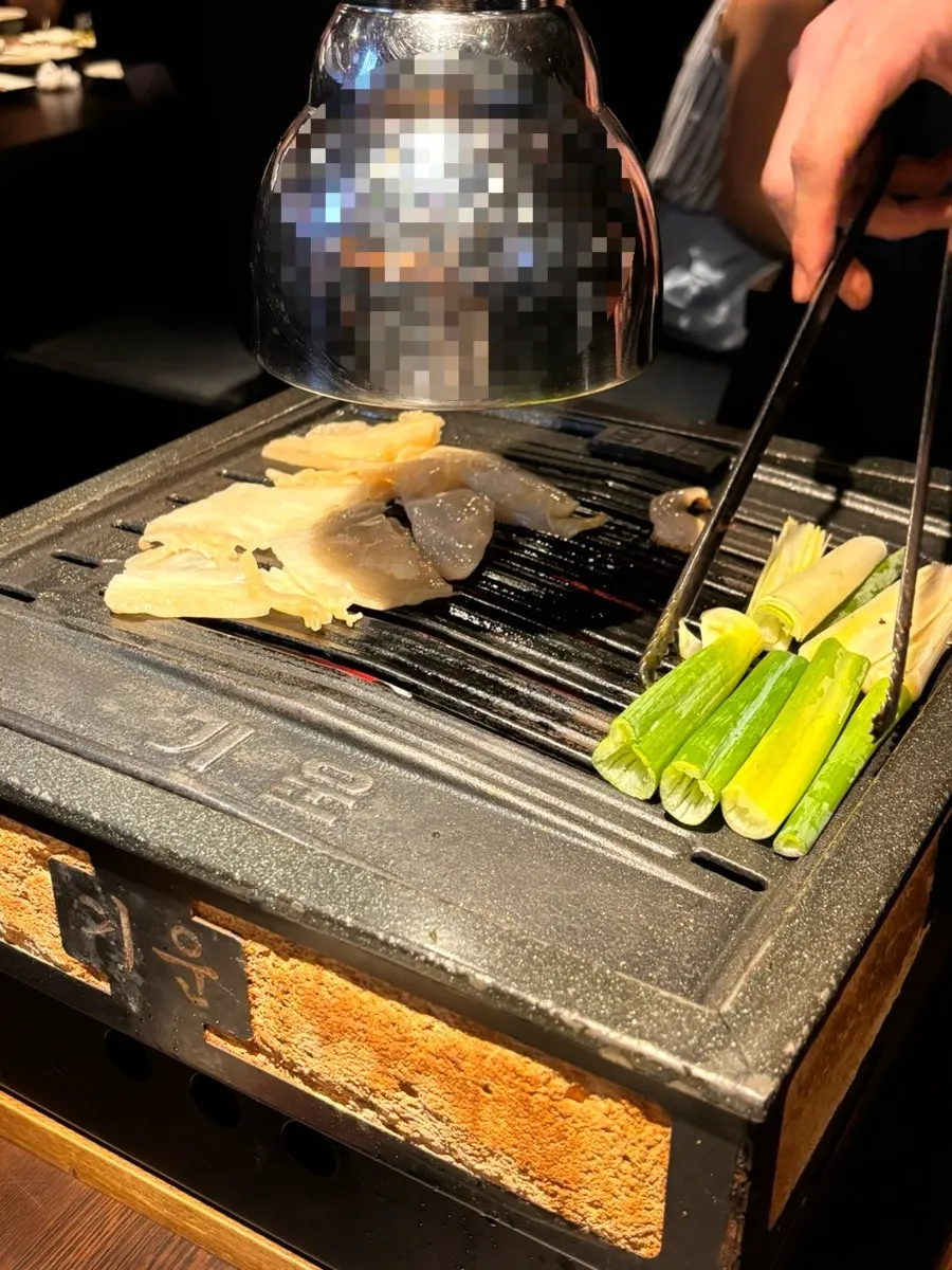 White kimchi and green onion grilling together on the plate