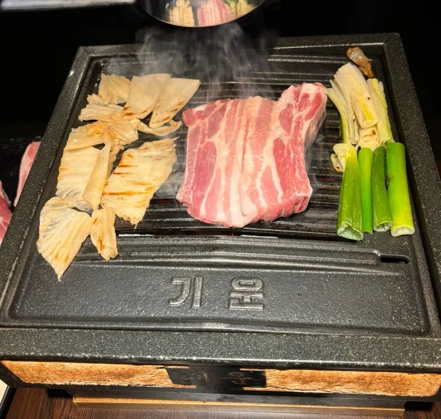 Charcoal grill topped with meat and vegetables