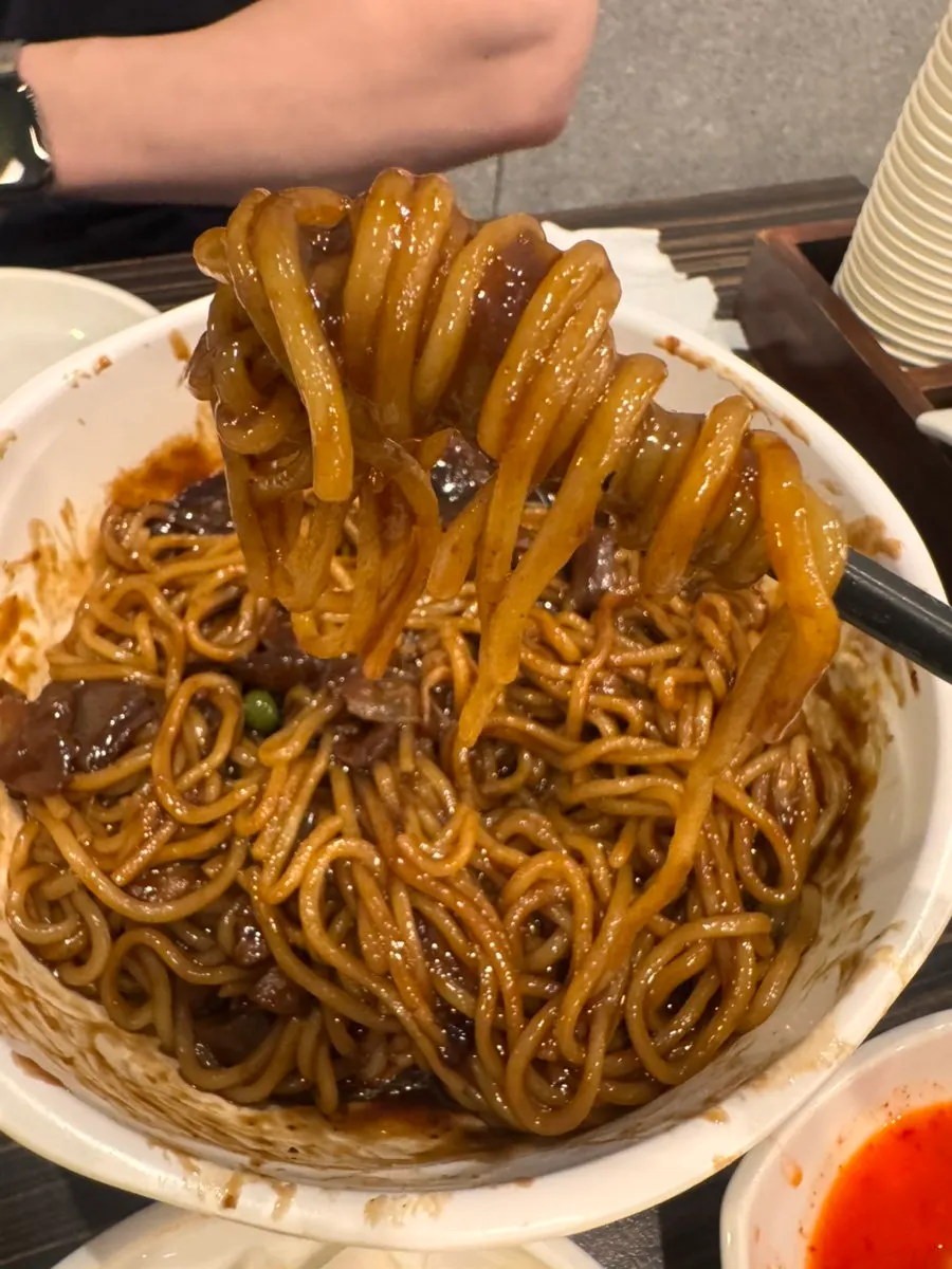 Jjajangmyeon noodles lifted with chopsticks