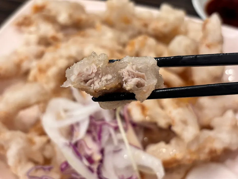 A piece of sweet and sour pork dipped in sauce