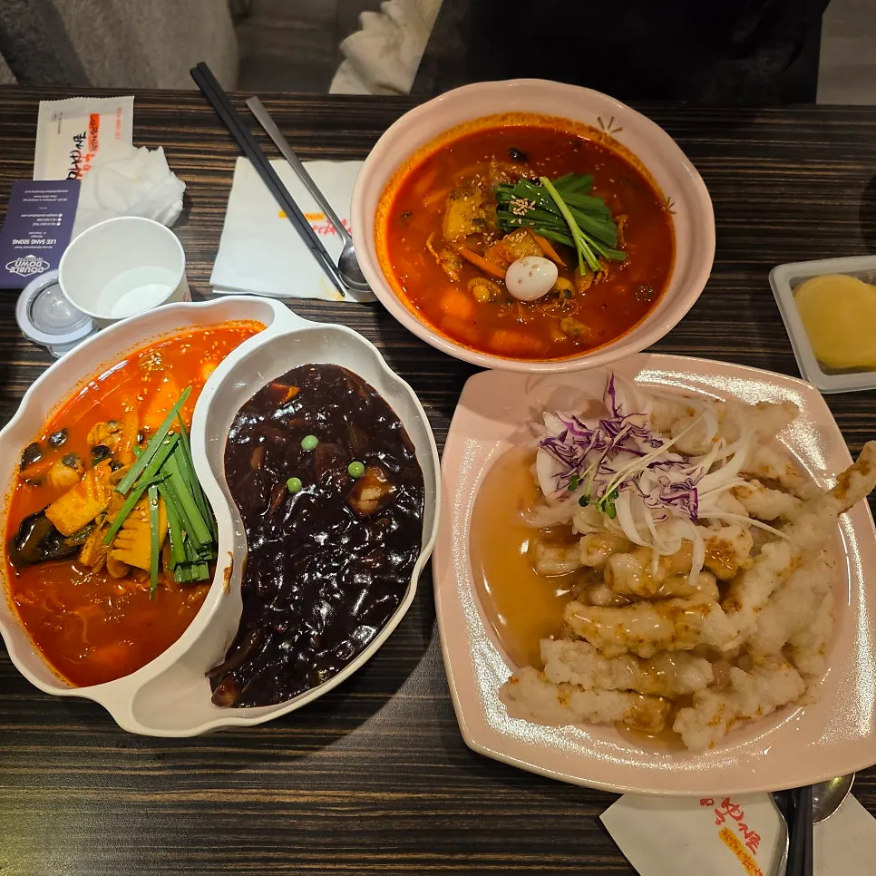 Table spread of jjamppong, jjamjjamyeon, and sweet and sour pork