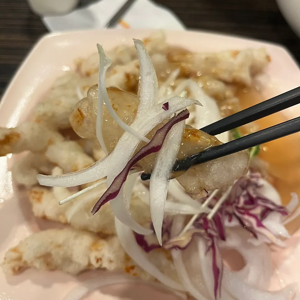 A piece of sweet and sour pork dipped in sauce