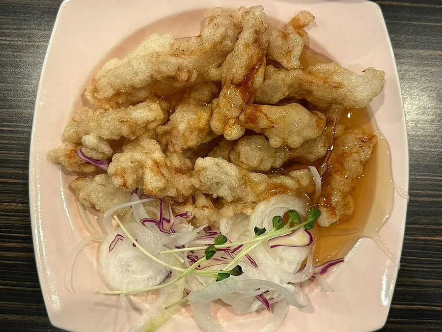 A plate of sweet and sour pork with sauce poured over it