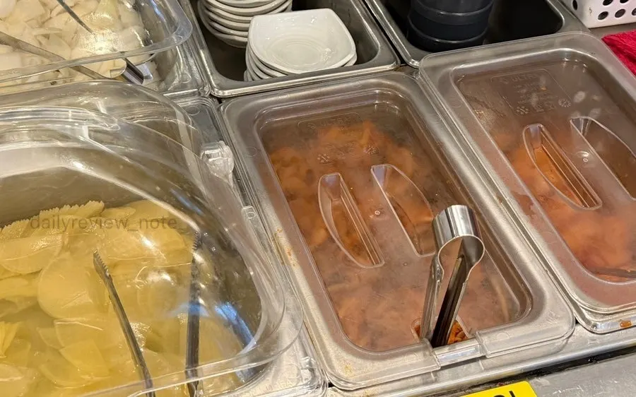 Self-service side dish corner with pickled radish, onion, and kimchi