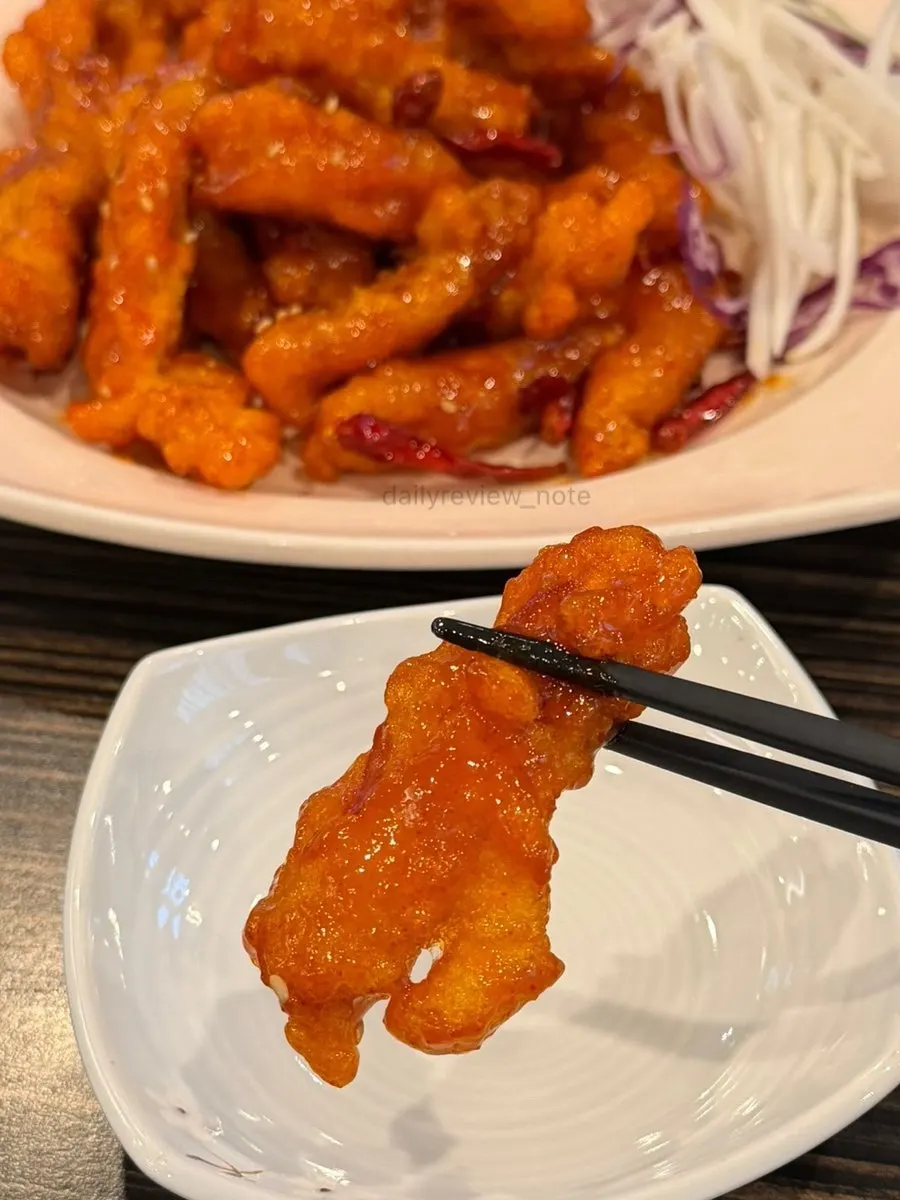 Vertical shot of Sichuan sweet and sour pork coated in spicy sauce