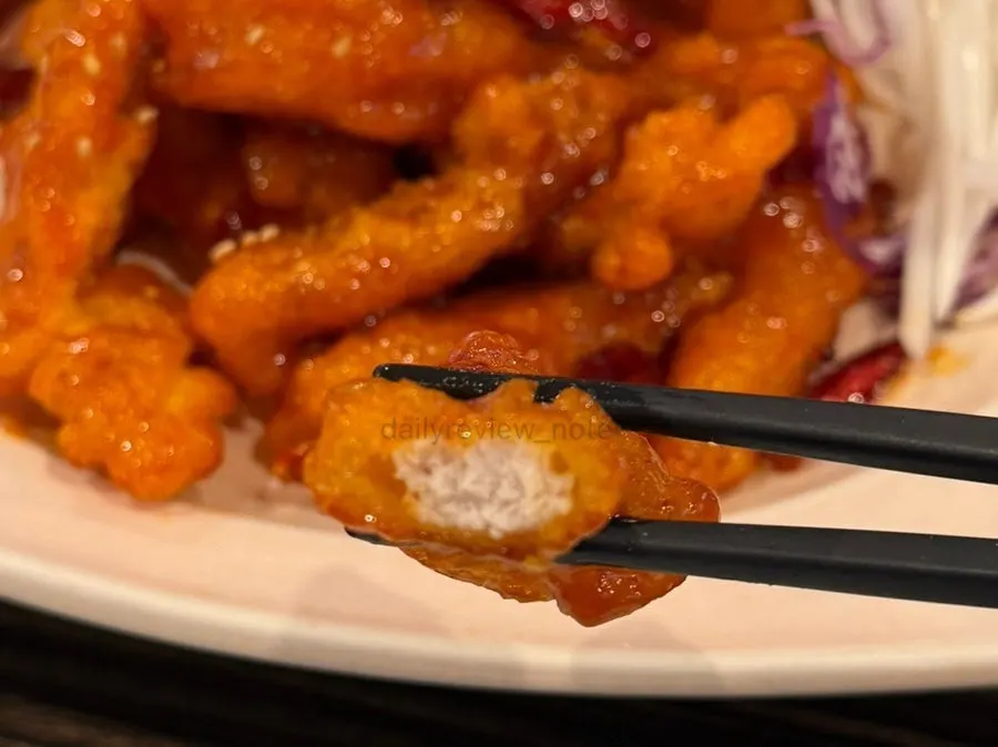 A large piece of sweet and sour pork picked up with chopsticks