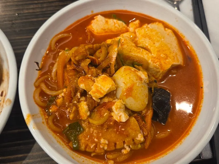 Broth filled with soft tofu, seafood, and zucchini