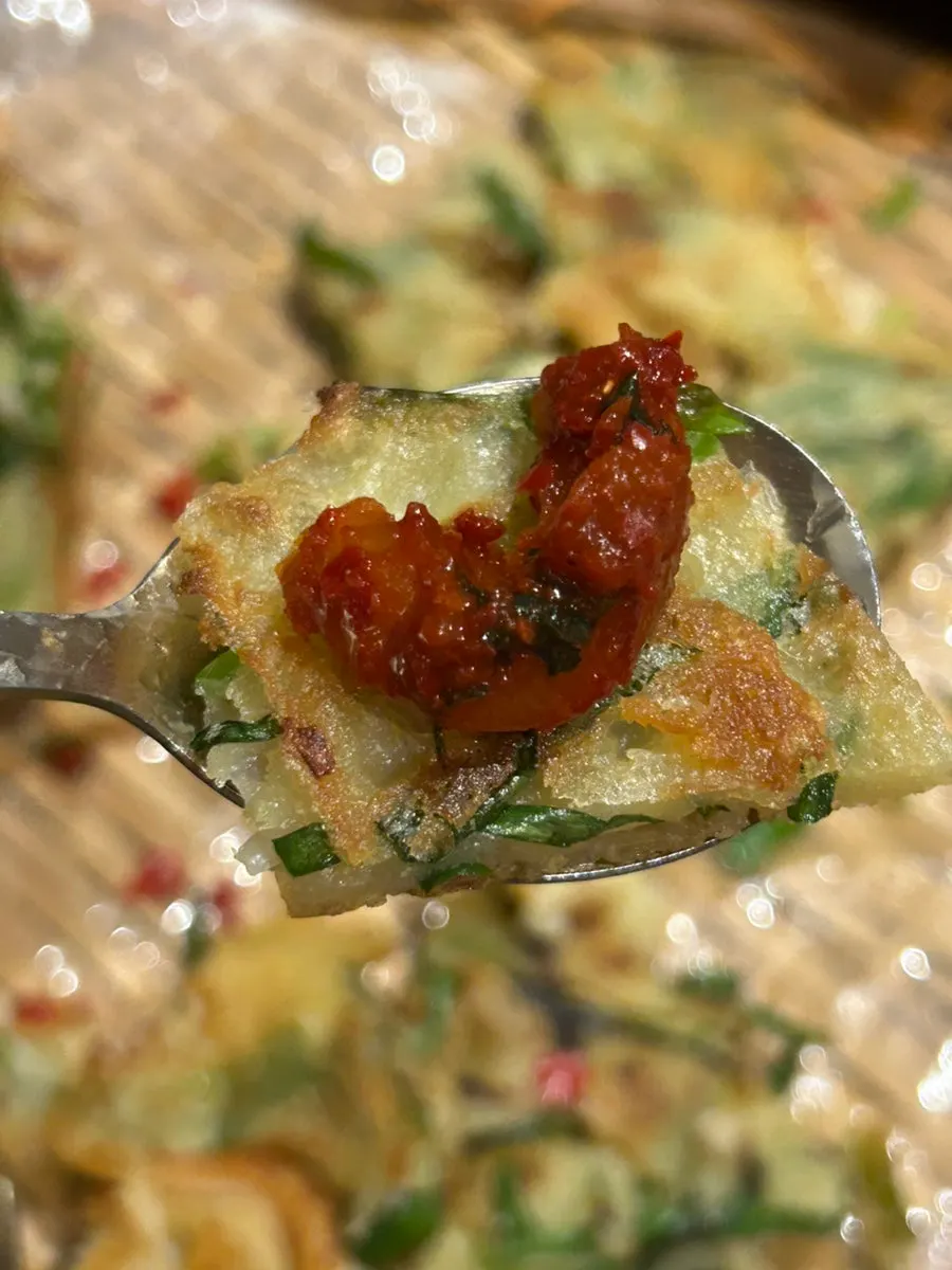 A piece of seafood pancake topped with cheongyang chili