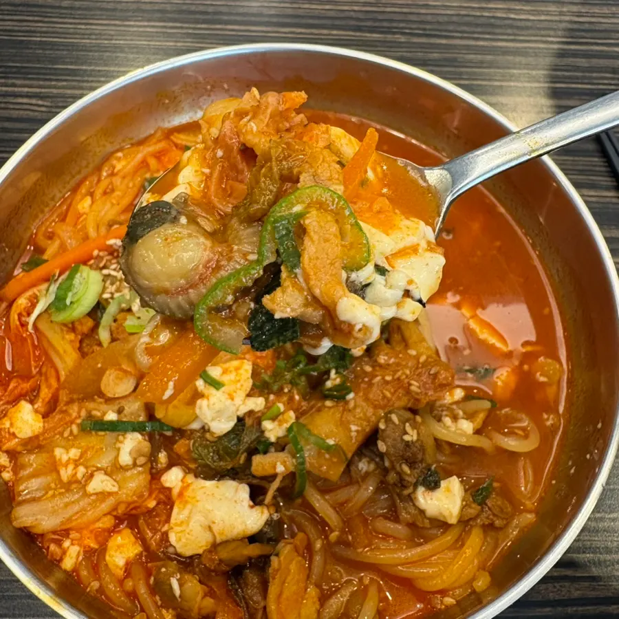 A scoop of noodles and soft tofu from the soup
