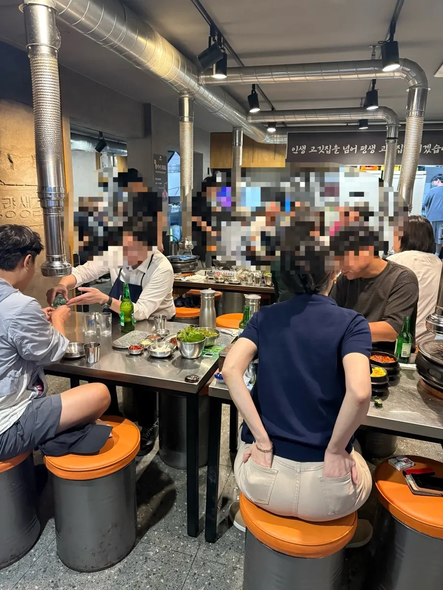 Interior with stools and stainless-steel tables full of diners