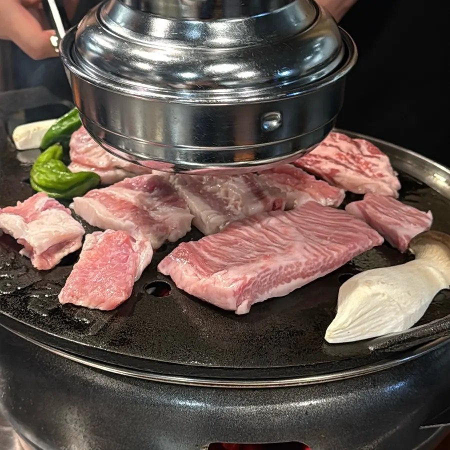 Staff grilling meat over charcoal
