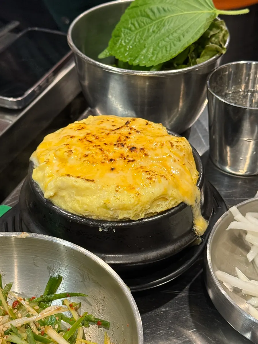 Golden cheesy steamed egg in an earthenware pot