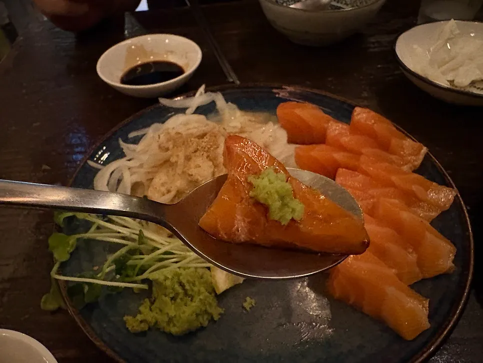 A piece of salmon with soy sauce and wasabi