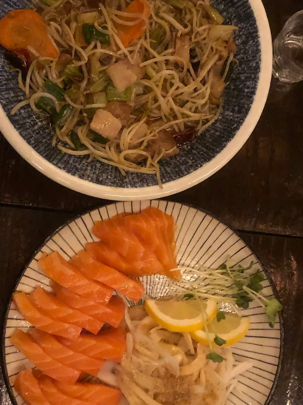 Salmon sashimi served with onion, radish sprouts, and lemon