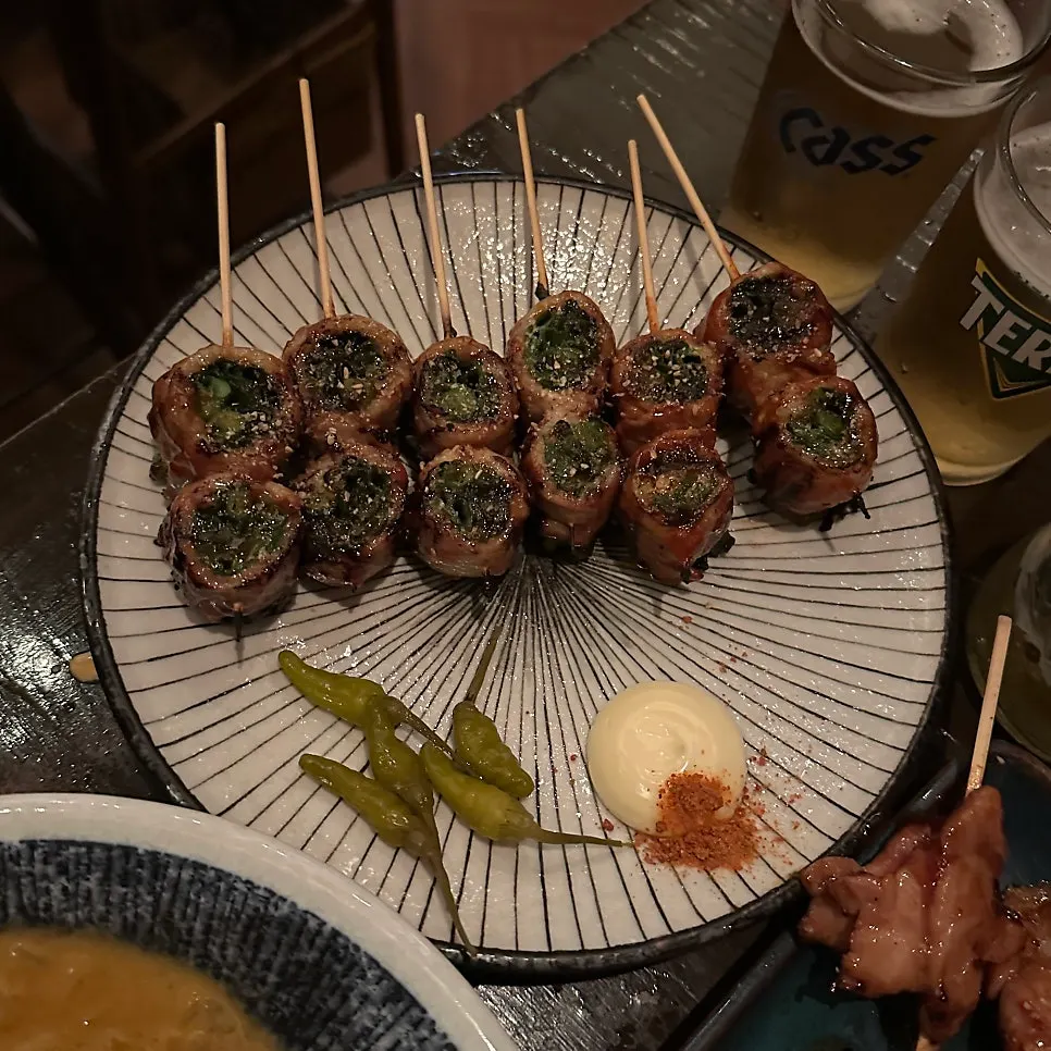 A plate of skewers next to a beer
