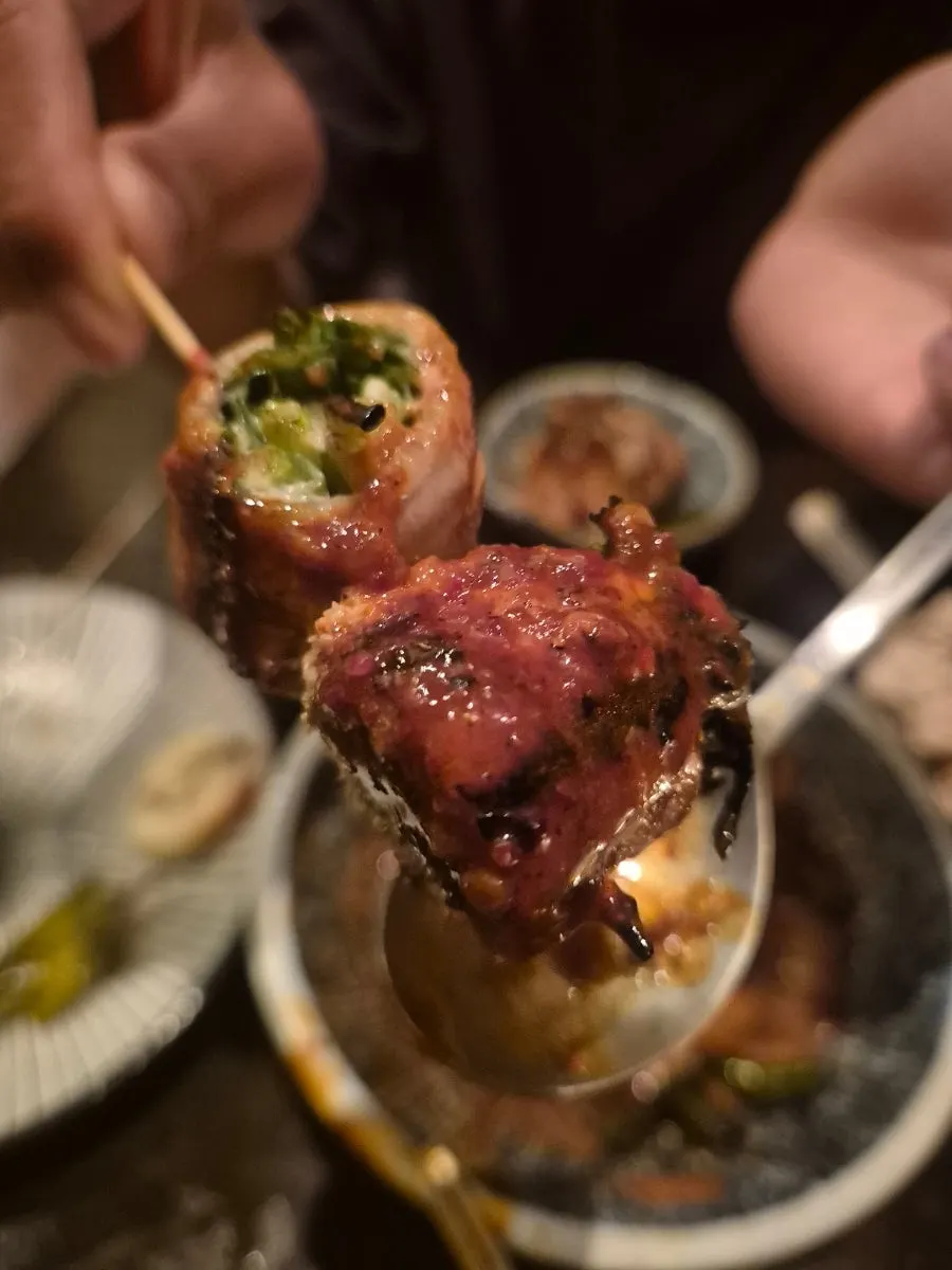 Close-up of a plate of pork belly scallion skewers