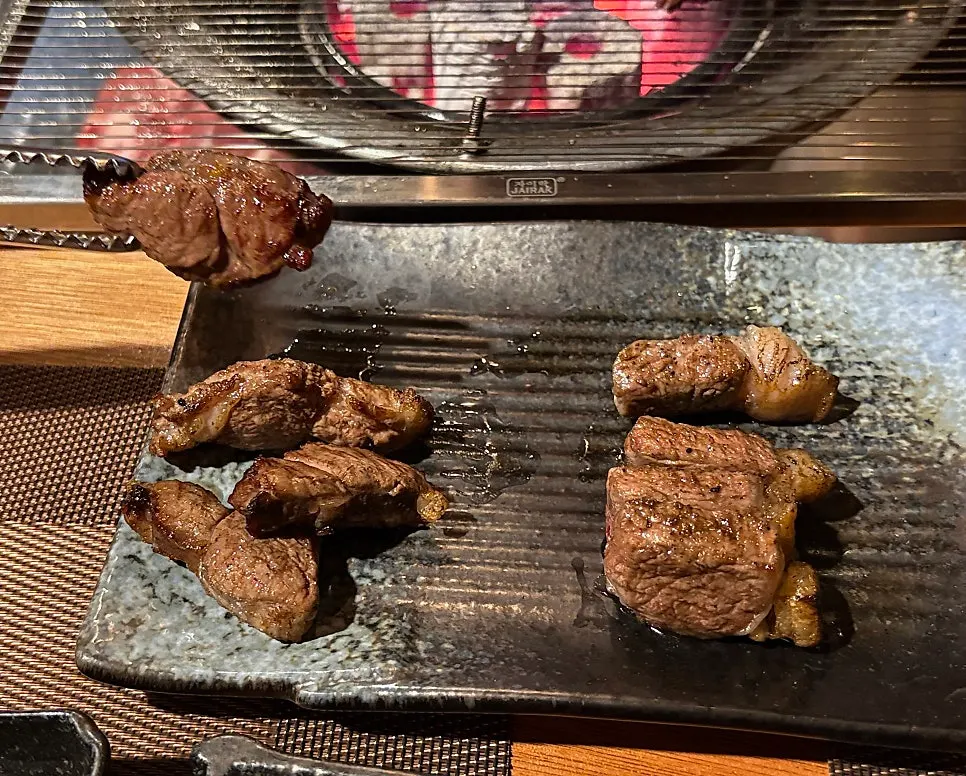Staff member grilling lamb ribs at the charcoal grill
