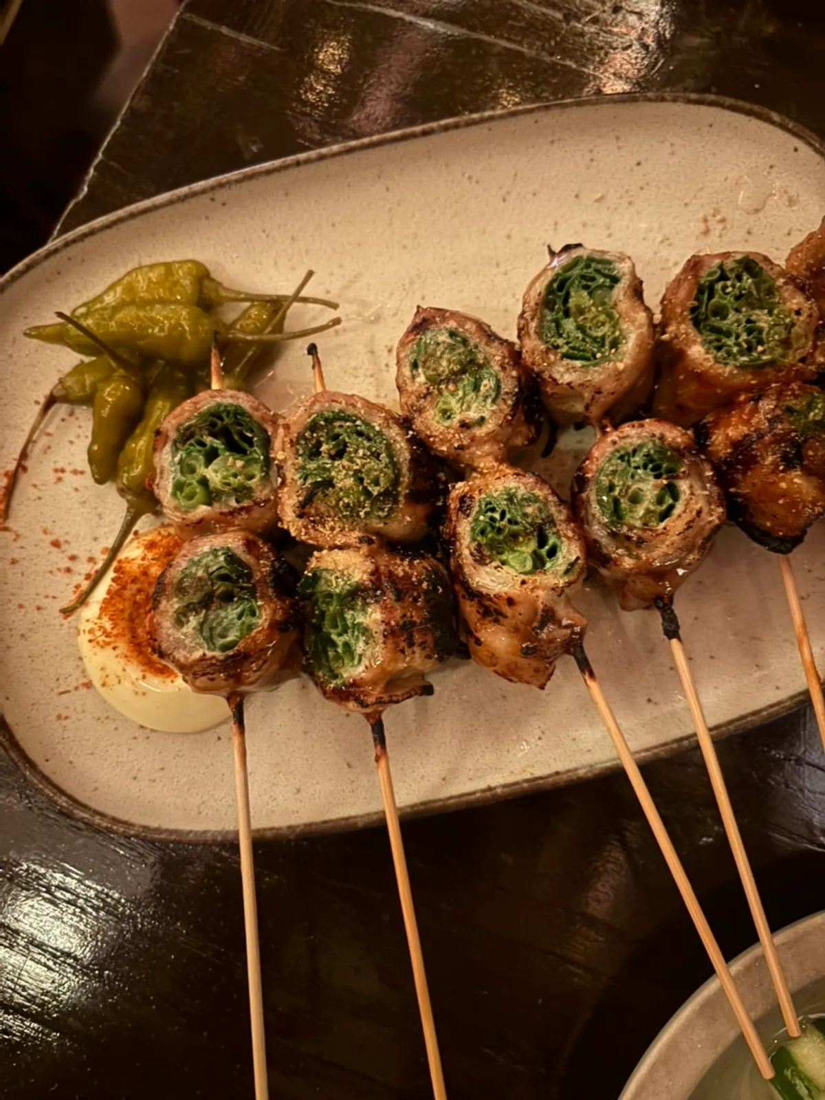 A plate of smoky pork belly scallion skewers