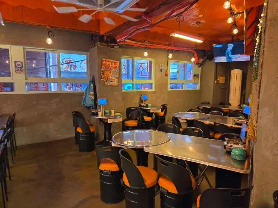 Pojangmacha-style decor with orange tent awnings and string lights