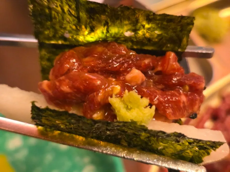 Yukhoe topped with egg yolk and sesame seeds, served with pear and seaweed
