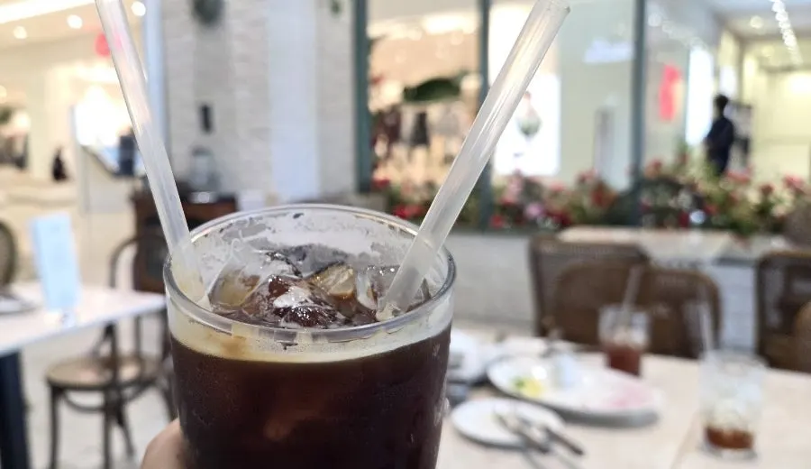 Mela iced americano with a straw sticking out