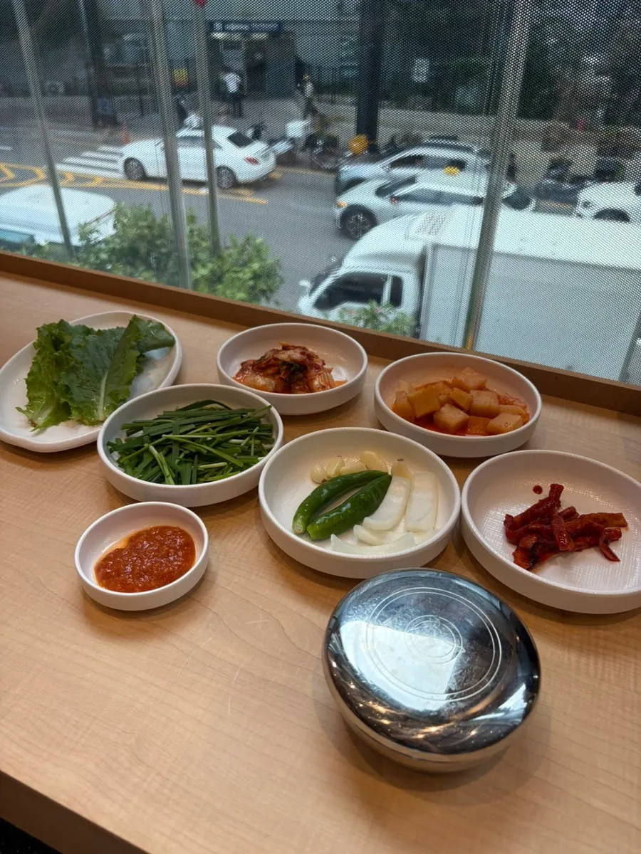 Side dishes of dried radish strips, diced kimchi, kimchi, lettuce, and ssamjang
