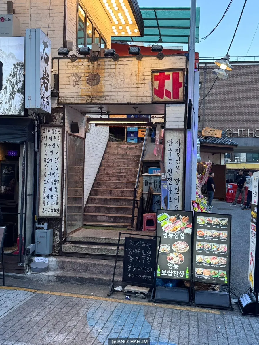Outdoor terrace seating with street-tent vibes facing the top of the stairs