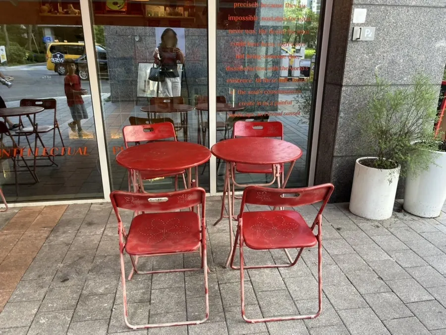 Red outdoor tables in front of the store