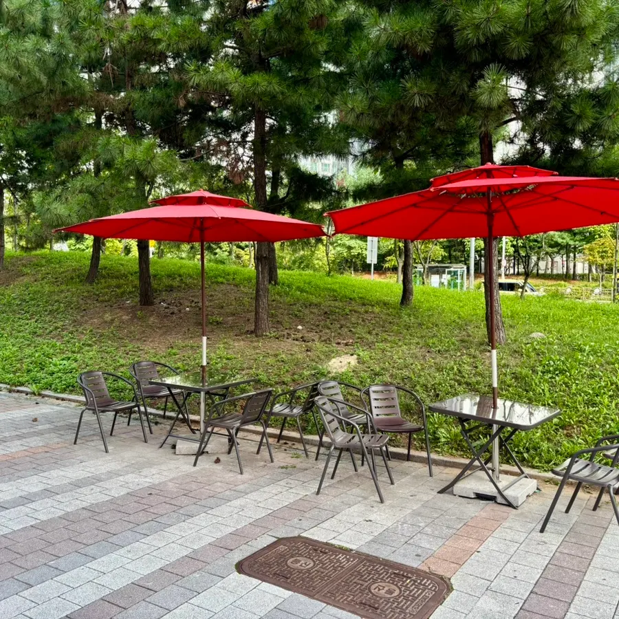 Outdoor parasol seating against a green backdrop
