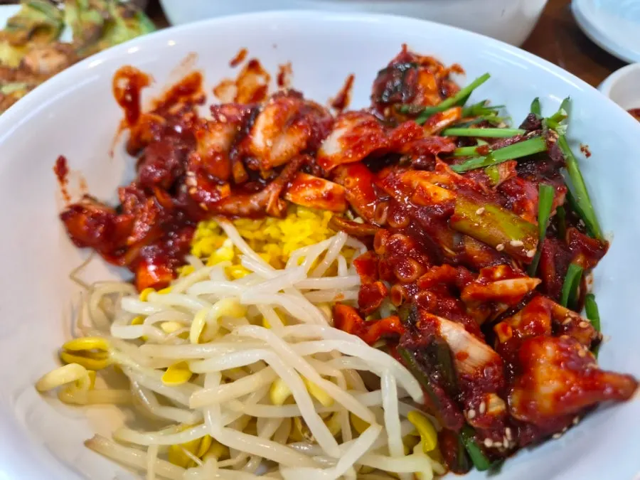 Bowl of turmeric rice mixed with bean sprouts and octopus stir-fry