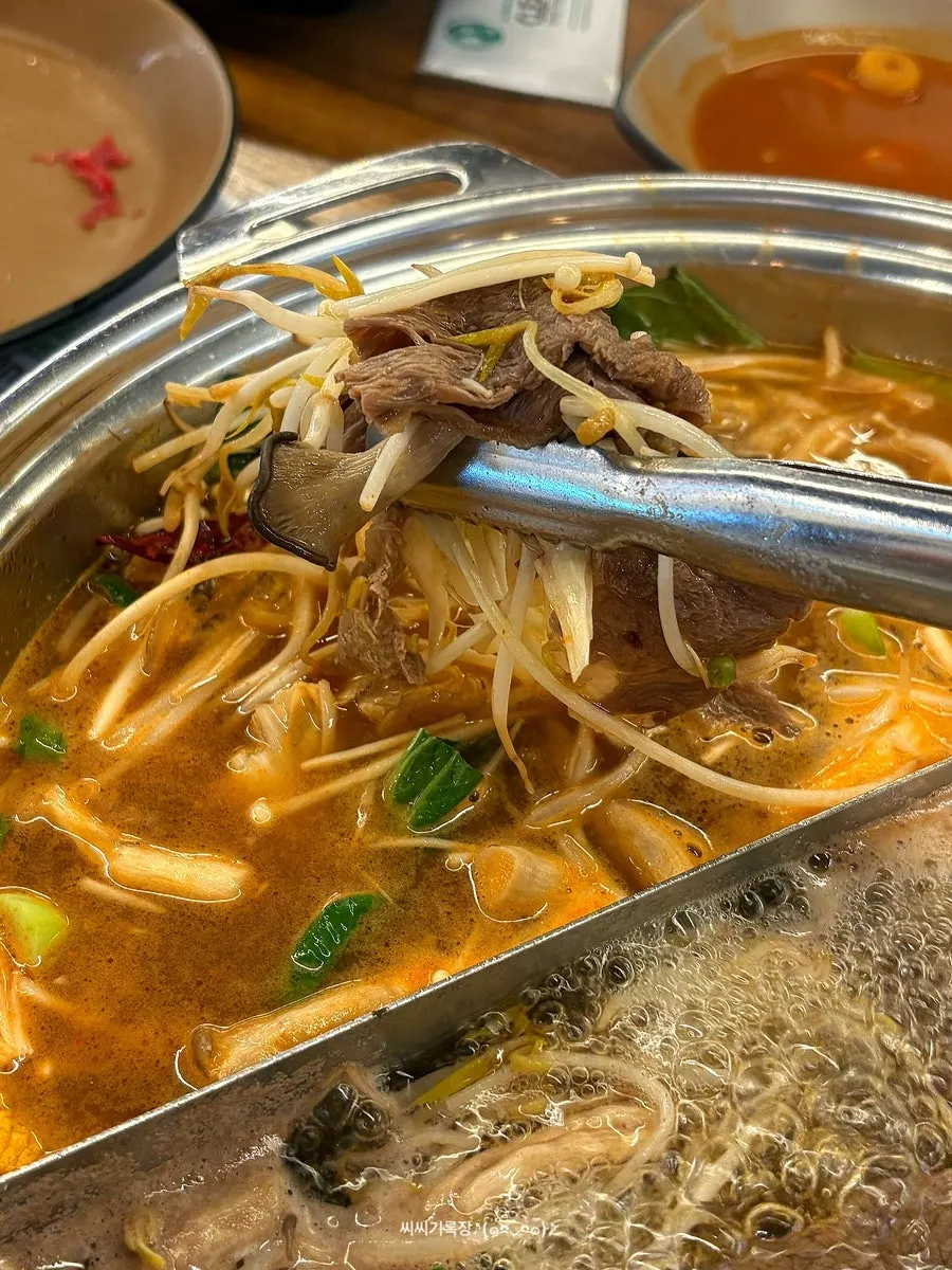 Thinly sliced beef cooking in the simmering broth