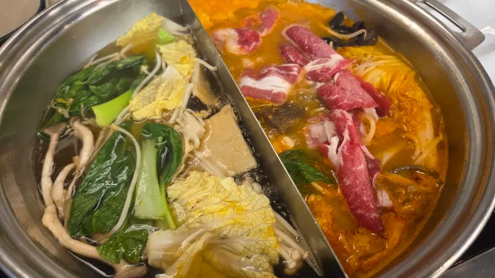 Rich beef bone mala broth simmering on one side of the pot