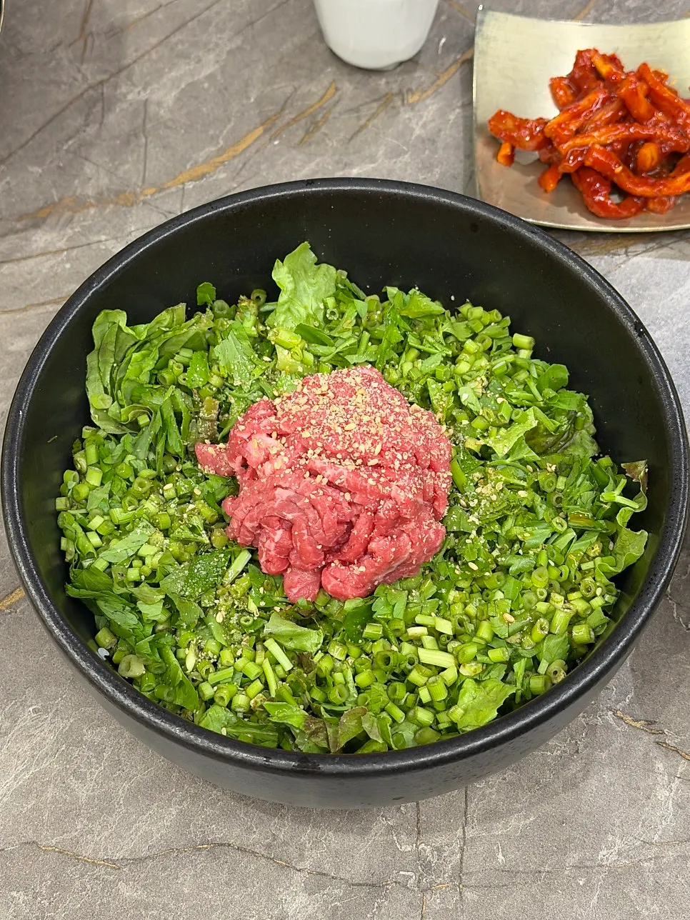 Hanwoo yukhoe bibimbap topped with minari and raw beef