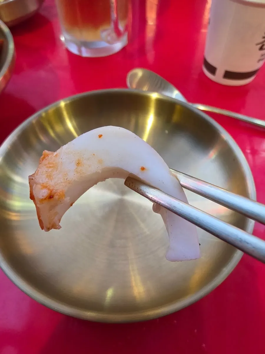 A piece of cuttlefish held with chopsticks
